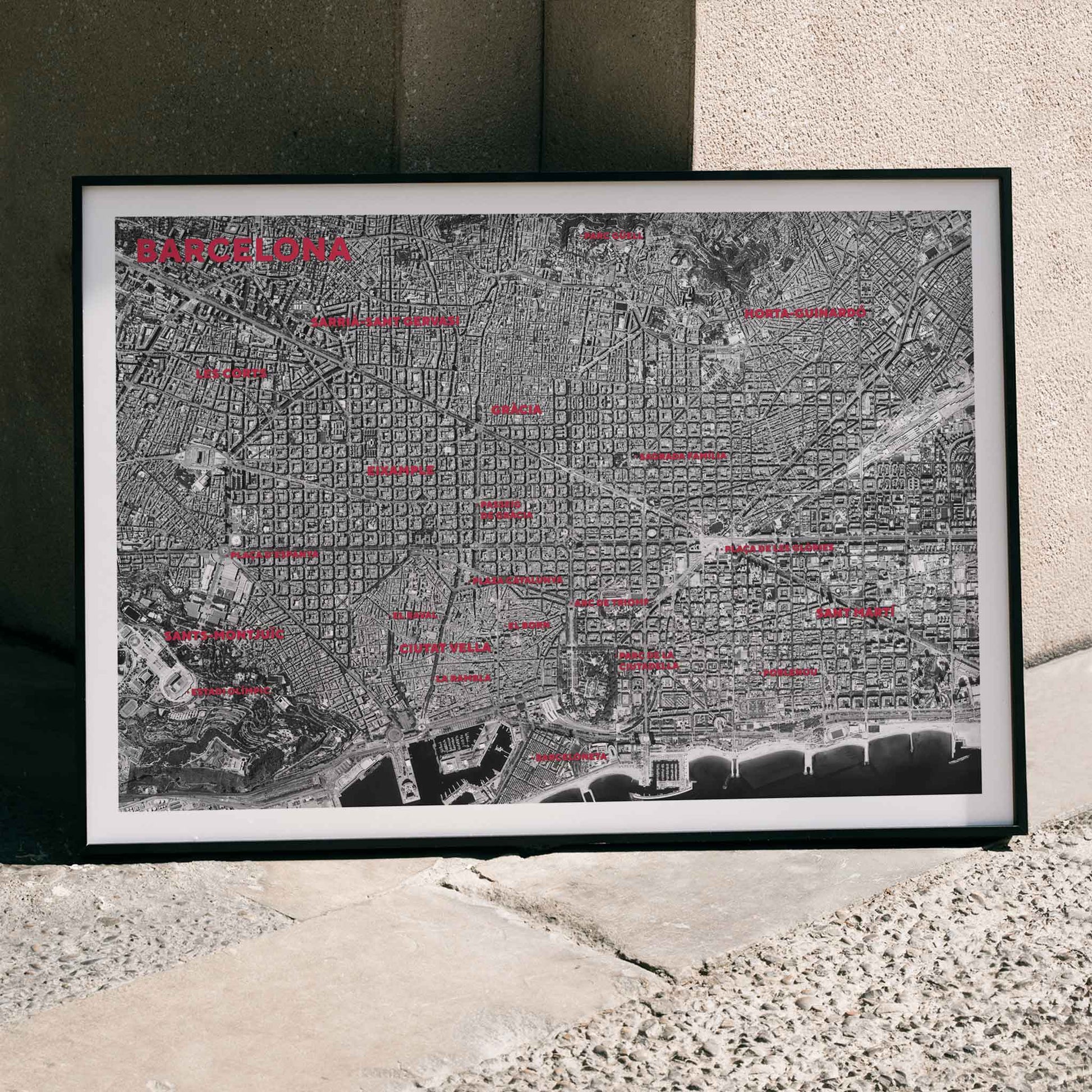 Moryarty Barcelona satellite city map poster in bold black and white aerial style showing city grid districts landmarks monuments and coastline, framed and displayed in home decor