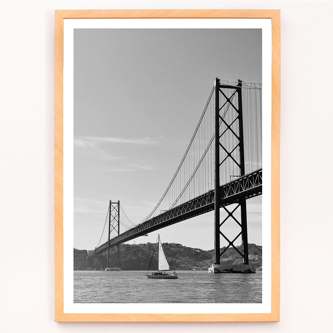 Lisbon Bridge Black and White Poster by Raphael Alves featuring a framed photograph of a suspension bridge and sailboat in the water, with black aluminium frame on white background