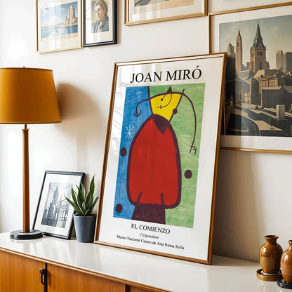 Exhibition poster of El Comienzo by Joan Miro with colorful abstract shapes and vibrant colors in a framed display, framed and displayed in home decor