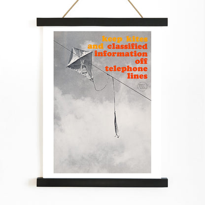 Black and white photo and poster of a kite tangled on a telephone line with bold warning text Keep kites and classified information off telephone lines, with wooden magnetic frame on white background