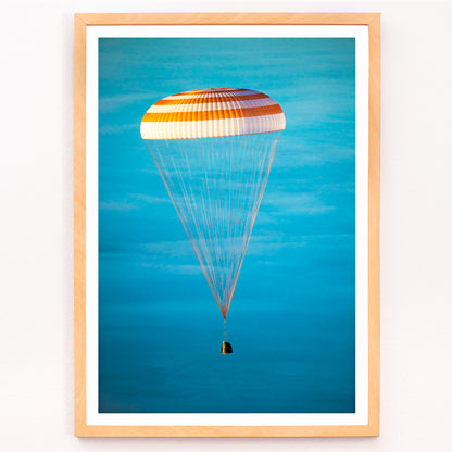 Closeup detail of Soyuz TMA-14M spacecraft descending with parachute against blue sky NASA Expedition 42 landing poster artwork