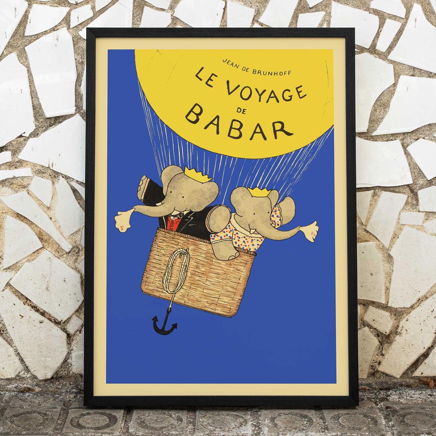 Le Voyage de Babar by Jean de Brunhoff illustration and poster featuring elephants in a hot air balloon with a yellow balloon on a blue background, framed and displayed in modern living room decor