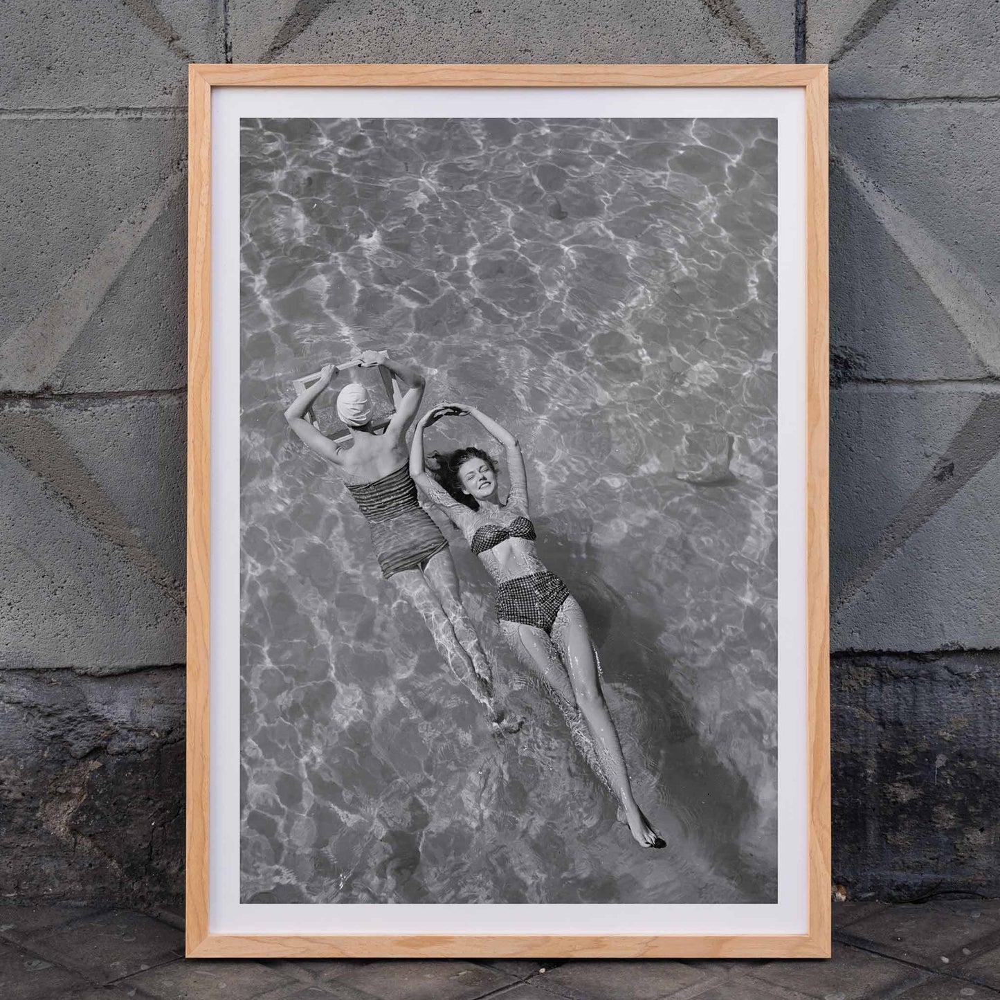 Fashion models in vintage bathing suits floating in a swimming pool artwork by Toni Frissell, framed and displayed in home decor