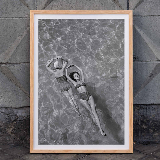 Fashion models in vintage bathing suits floating in a swimming pool artwork by Toni Frissell, framed and displayed in home decor