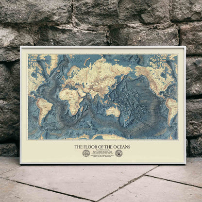 World map artwork showing ocean floors titled The Floor of the Oceans bathymetric map poster, framed and displayed in home decor