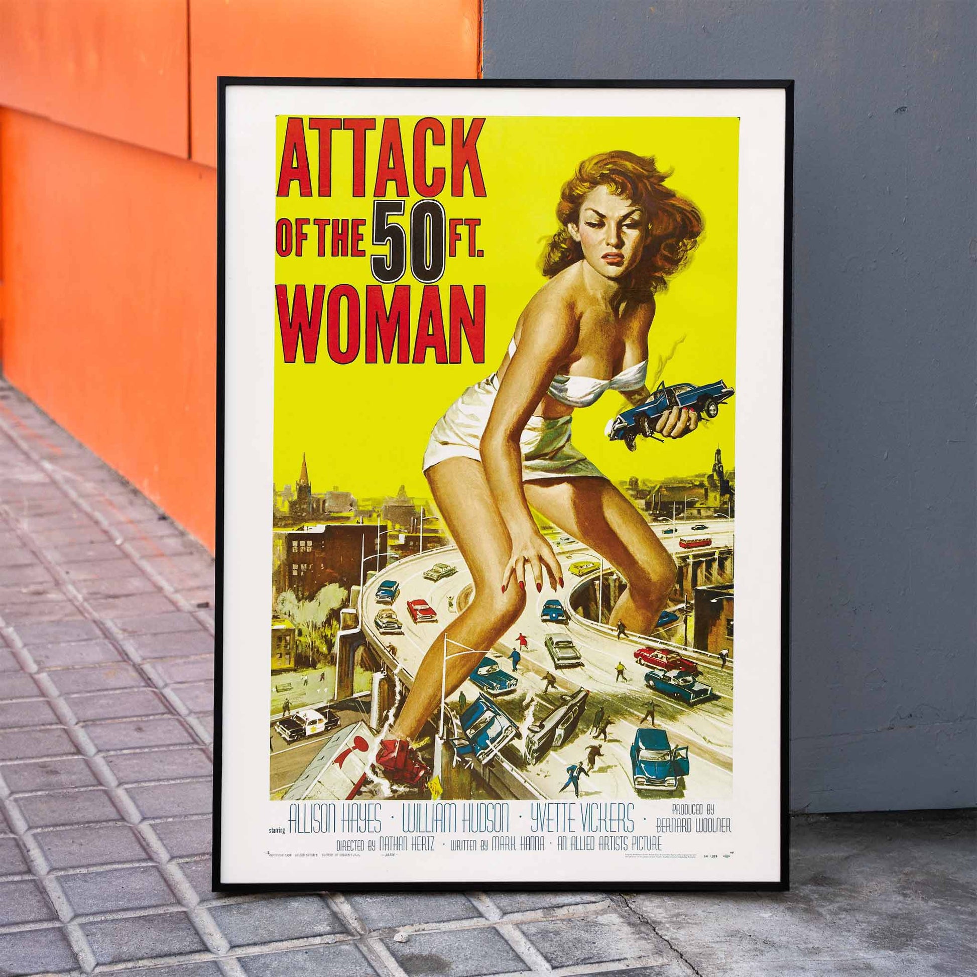 Giant woman towering over city and highway holding cars Attack of the 50ft Woman poster artwork by Reynold Brown, framed and displayed in home decor