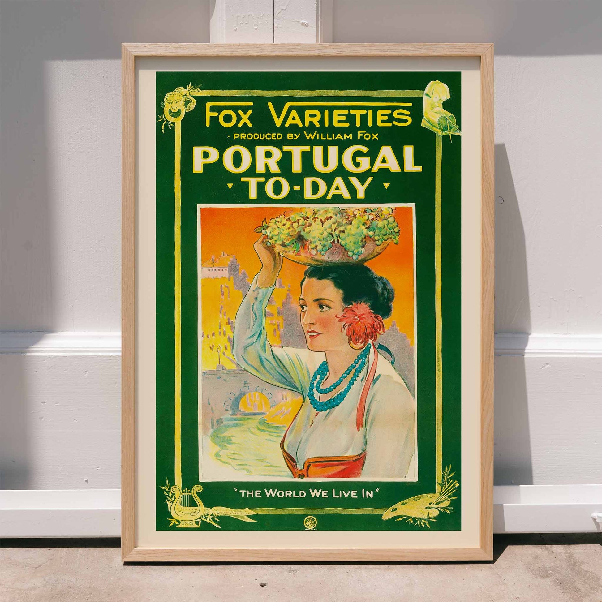 Colorful vintage poster of Portugal Today featuring a woman in traditional attire carrying grapes and fruit on her head with vibrant backdrop by William Fox and Anonymous, framed and displayed in home decor