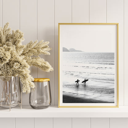 Black and white poster of surfers walking along the beach Surfers walking on the beach artwork, framed and displayed in home decor
