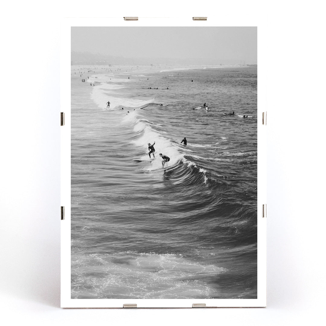 Black and white surfers riding waves at Venice Beach coastal wall art poster ideal for home decor, framed and displayed in modern living room decor