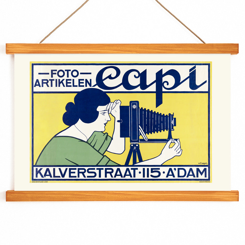 Vintage art deco poster of a woman using a vintage camera at Capi Camera Shop by Johann Georg van Caspel, with wooden magnetic frame on white background