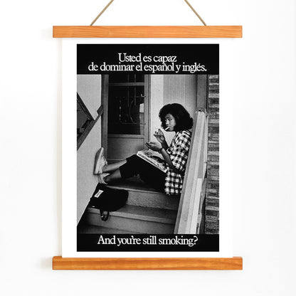 Young woman reading and smoking on stairs in bilingual anti-smoking poster by US Department of Health and Human Services titled Usted es capaz de dominar el español y inglés and you are still smoking, with wooden magnetic frame on white background